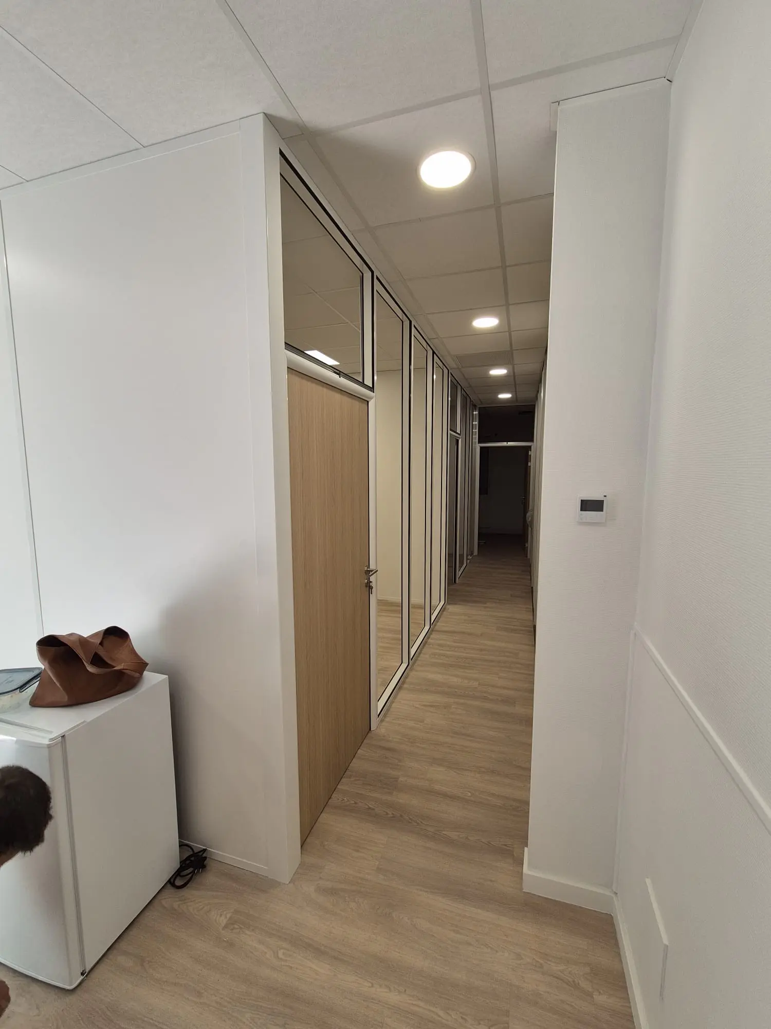 Couloir de bureaux desservi par des portes en chêne clair, menuiserie intérieure